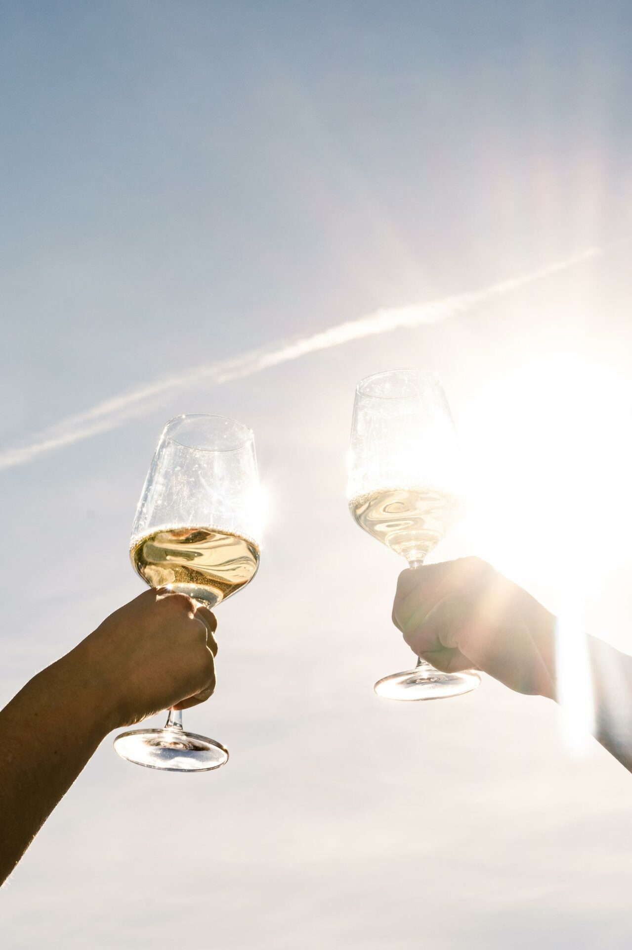 Two filled wine glasses are held in the air.